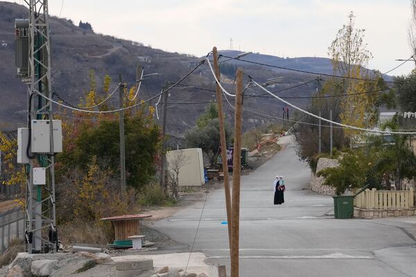 A woman holds her child near the so-called Alpha Line that separates the Israeli-annexed Golan Heights from Syria, in the town of Majdal Shams, Wednesday, Dec. 11, 2024. (AP Photo/Matias Delacroix)