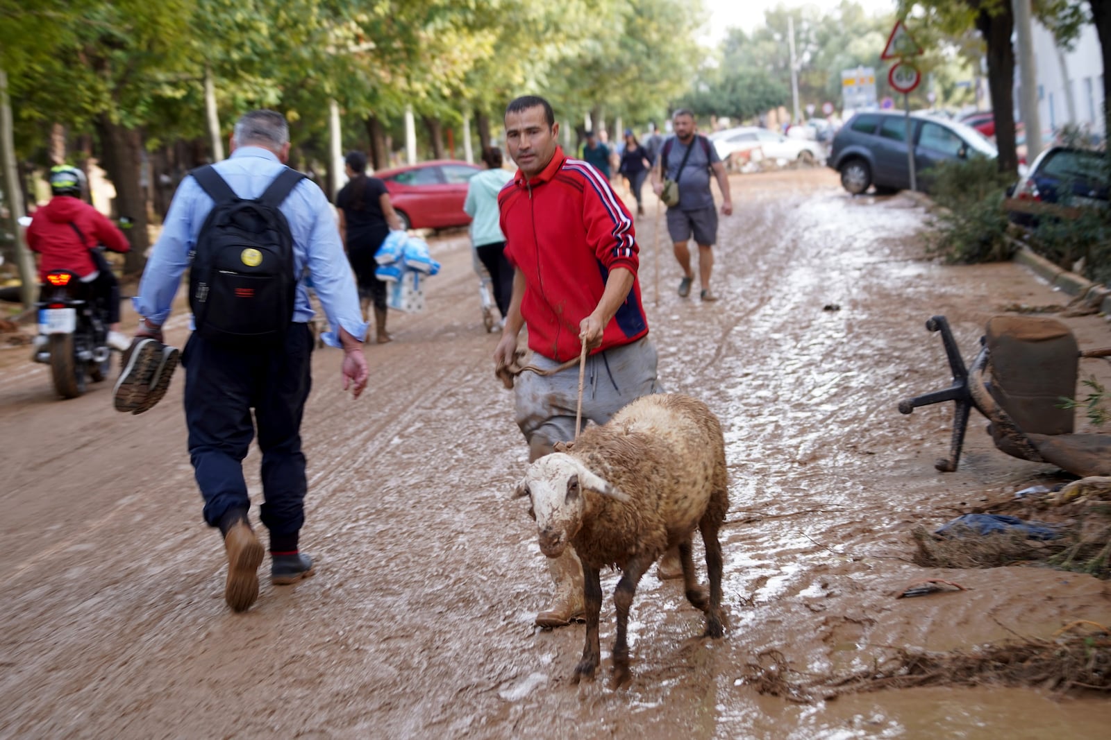 People walk on muddy roads after floods in Valencia, Spain, Wednesday, Oct. 30, 2024. (AP Photo/Alberto Saiz)