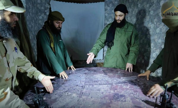 FILE - This undated file photo released by a militant group in 2016, shows Abu Mohammed al-Golani of the militant Levant Liberation Committee and the leader of Syria's al-Qaida affiliate, second right, discussing battlefield details with field commanders over a map, in Aleppo, Syria. (Militant UGC via AP, File)