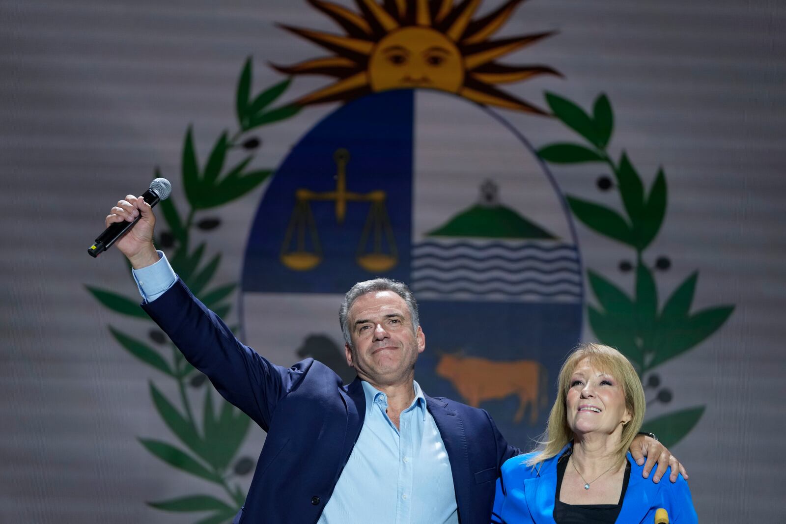 Frente Amplio presidential candidate Yamandu Orsi and running mate Carolina Cosse wave to supporters outside of a hotel after general elections polls closed in Montevideo, Uruguay, Sunday, Oct. 27, 2024. (AP Photo/Natacha Pisarenko)