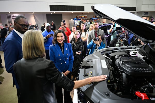 Michigan Gov. Gretchen Whitmer, center, and Lt. Gov. Garlin Gilchrist II, left, are given a tour of a Stellantis vehicle by product specialist Karen Bernard, second from left, at the Detroit Auto Show, Wednesday, Jan. 15, 2025, in Detroit. (AP Photo/Jose Juarez)