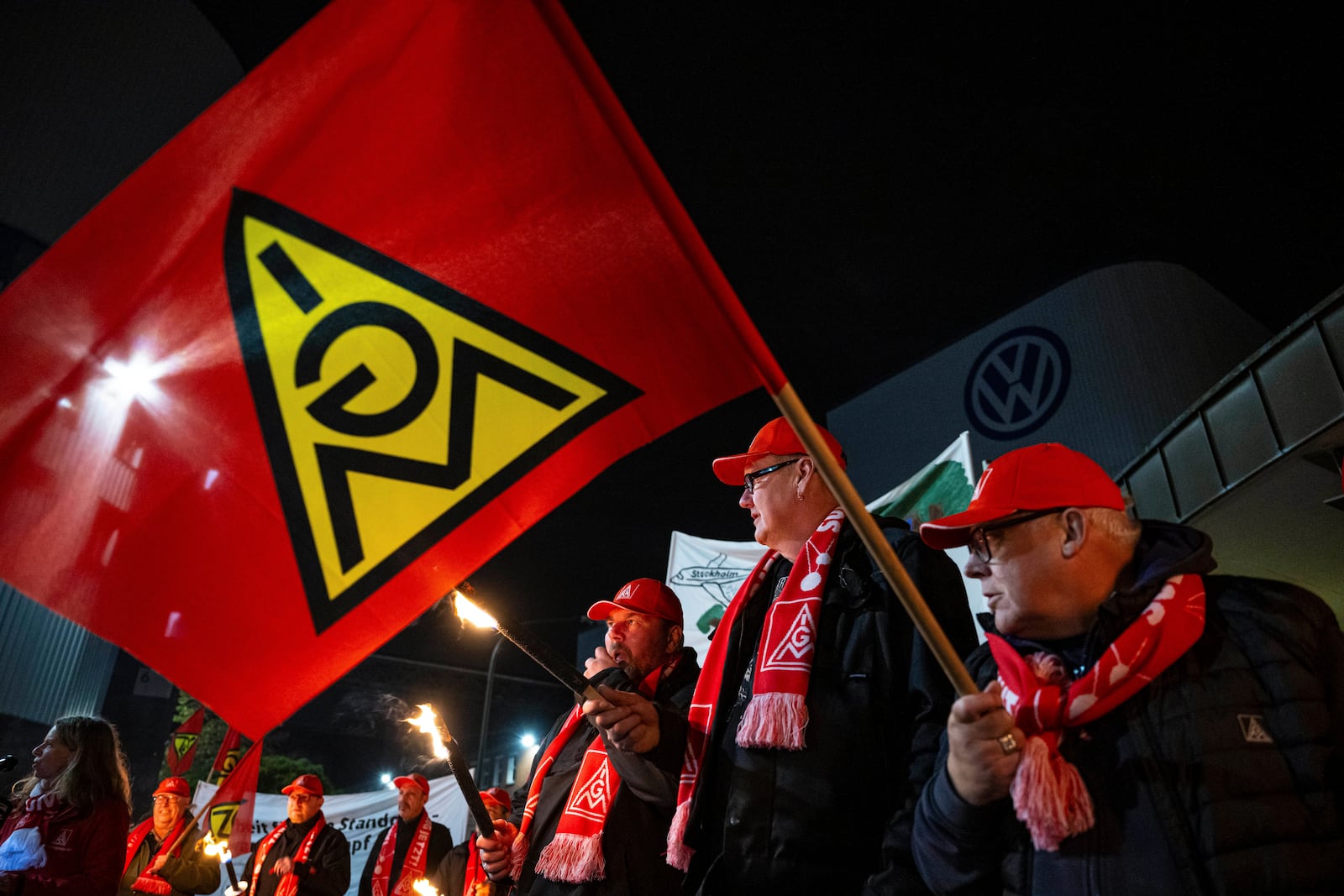 Volkswagen employees stand with torches in front of the VW plant in Osnabruck, Germany, Tuesday, Oct. 29, 2024. (Guido Kirchner/dpa via AP)