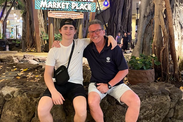 In this October 2023 photo provided by the Holdsworth family, Wayne Holdsworth sits with his son Mac on a family holiday in Hawaii. (Maggie Holdsworth via AP)