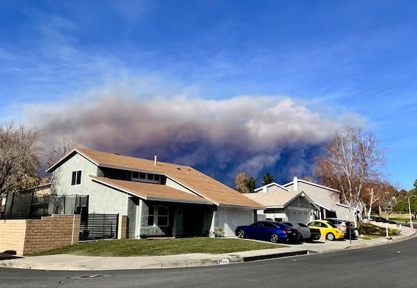 A large plume of smoke caused by the Hughes Fire rises from Castaic Lake as seen from a neighborhood of Santa Clarita, Calif., Wednesday, Jan. 22, 2025. (AP Photo/Marcio Jose Sanchez)