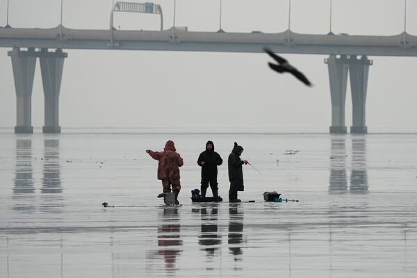 Men fish on melting ice not far from shore on the Gulf of Finland in St. Petersburg, Russia, Wednesday, Jan. 29, 2025, during unusually warm weather with temperatures at 5 degrees Celsius (41 degrees Fahrenheit). (AP Photo/Dmitri Lovetsky)