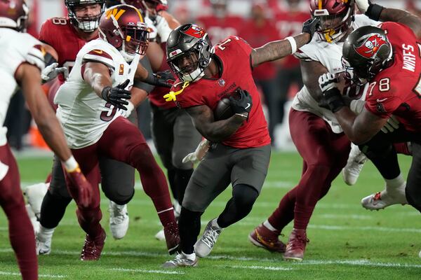 Tampa Bay Buccaneers running back Bucky Irving, middle, runs against the Washington Commanders during the second half of an NFL wild-card playoff football game in Tampa, Fla., Sunday, Jan. 12, 2025. (AP Photo/Chris O'Meara)