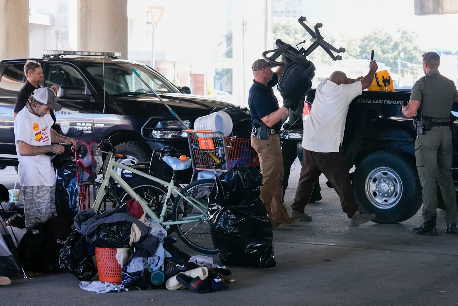 Louisiana Wildlife and Fisheries agents assist state police as they give instructions to people living in a homeless encampment to move to a different pre-designated location as they perform a sweep in advance of a Taylor Swift concert in New Orleans, Wednesday, Oct. 23, 2024. (AP Photo/Gerald Herbert)