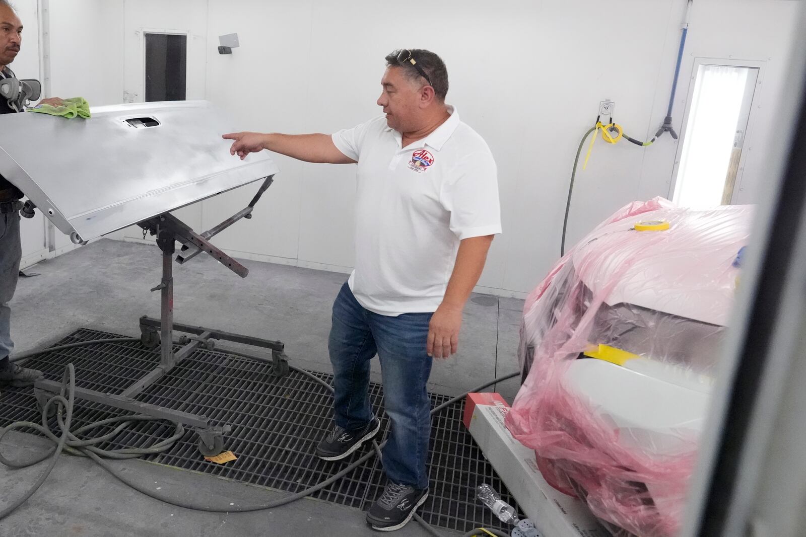 Business owner Alex Salguero checks out a worker's progress at his auto body shop in Lewisville, Texas, Wednesday, Oct. 2, 2024. (AP Photo/LM Otero)