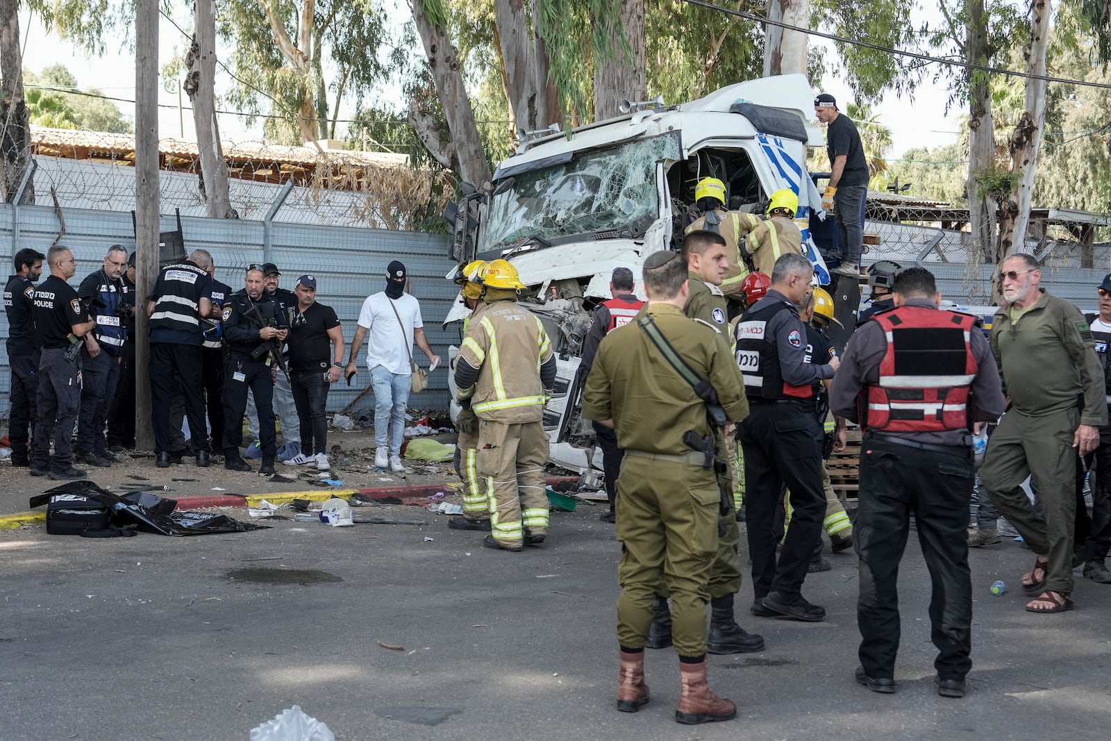 Israeli police and rescue workers climb on a truck to inspect the body of a driver that rammed into a bus stop near the headquarters of Israel's Mossad spy agency, wounding dozens of people, according to Israel's Magen David Adom rescue service in Tel Aviv, Israel, Sunday, Oct. 27, 2024. (AP Photo/Oded Balilty)