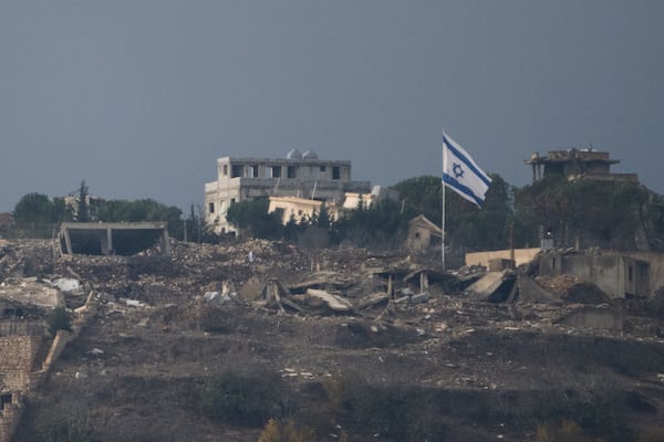 An Israeli flag stands next to damaged buildings on an area in southern Lebanon as seen from northern Israel, Tuesday, Nov. 19, 2024. (AP Photo/Leo Correa)