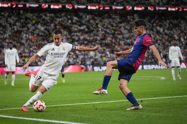 Real Madrid's Lucas Vazquez, left, challenges for the ball with Barcelona's Pedri during the Spain Super Cup final soccer match between Real Madrid and Barcelona at King Abdullah Stadium in Jeddah, Saudi Arabia, Sunday, Jan. 12, 2025. (AP Photo/Altaf Qadri)