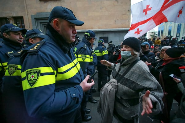 A woman gestures standing in front of police blocking the entrance of the Parliament's building during a rally to demand new parliamentary elections in the country, in Tbilisi, Georgia, Monday, Nov. 25, 2024. (AP Photo/Zurab Tsertsvadze)