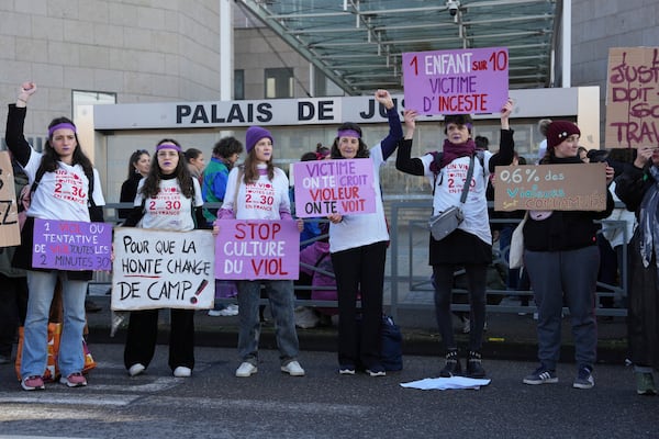 FILE - Activists hold posters in front of the Palace of Justice during a women's rights demonstration on Dec. 14, 2024, in Avignon, southern France, where the trial of dozens of men accused of raping Gisèle Pelicot while she was drugged and rendered unconscious by her husband is taking place. (AP Photo/Aurelien Morissard, File)