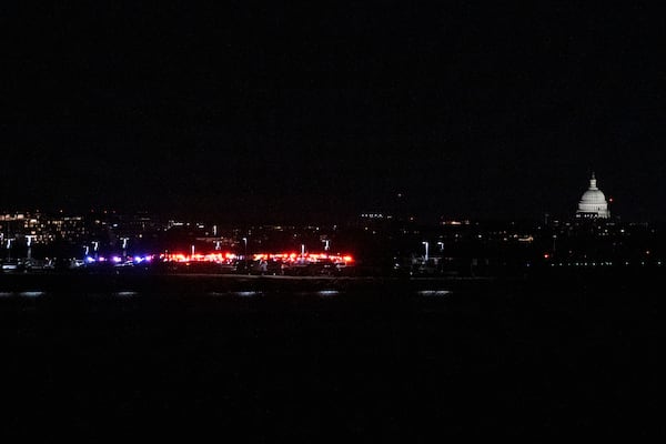 Emergency vehicles stage at Reagan National Airport, Wednesday night, Jan. 29, 2025 in Washington. The U.S. Capitol is seen right. (AP Photo/Kevin Wolf)