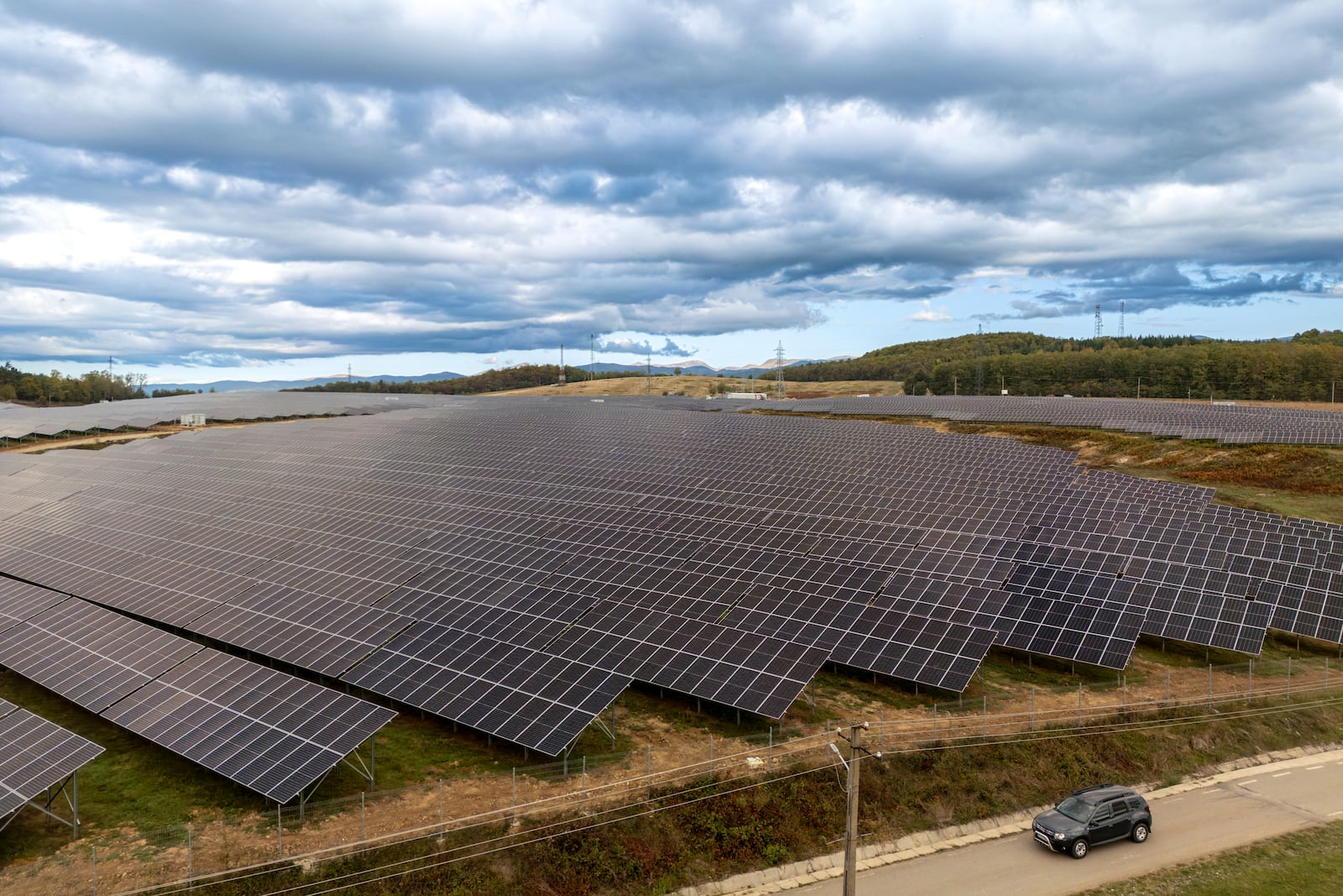 A car drives by a solar farm, managed by the Chinese CHINT smart energy solutions provider in Slatioara, southern Romania, Saturday, Oct. 12, 2024. (AP Photo/Vadim Ghirda)