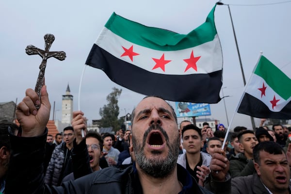 A Syrian Christian man holds up a cross and shouts slogans in Damascus, Syria, Tuesday, Dec. 24, 2024, during a protest march after a Christmas tree was set on fire in Hamah city on Sunday. (AP Photo/Hussein Malla)