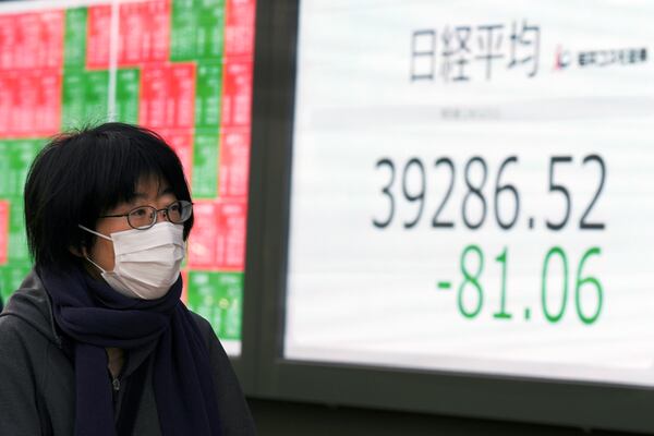 A person walks in front of an electronic stock board showing Japan's Nikkei index at a securities firm Wednesday, Dec. 11, 2024, in Tokyo. (AP Photo/Eugene Hoshiko)