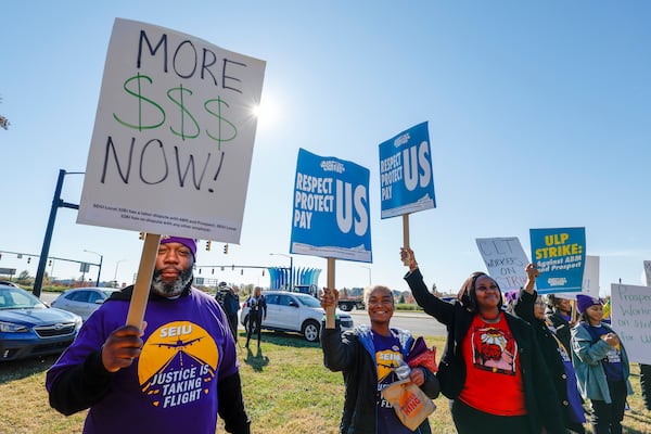 Airport workers wave signs as they march in front of the Charlotte Douglas International Airport in Charlotte, N.C., Monday, Nov. 25, 2024. (AP Photo/Nell Redmond)