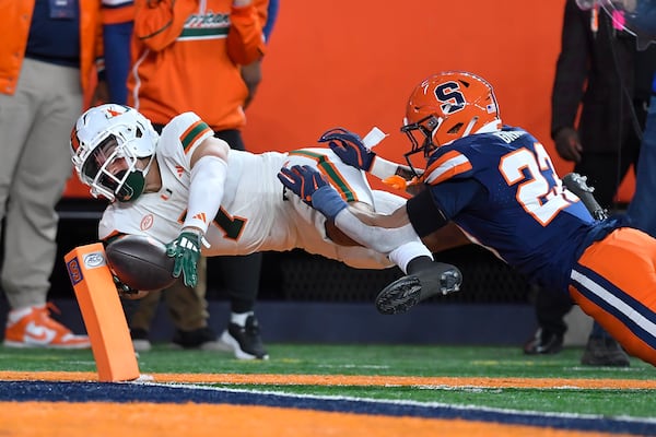 Miami wide receiver Xavier Restrepo (7) dives for the pylon to score while defended by Syracuse defensive back Devin Grant (23) during the first half of an NCAA football game Saturday, Nov. 30, 2024, in Syracuse, N.Y. (AP Photo/Adrian Kraus)