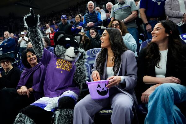 Current Las Vegas Aces player and former Washington guard Kelsey Plum, center, laughs with mascot Harry the Husky before her jersey retirement ceremony during an NCAA college basketball game between Washington and Purdue, Saturday, Jan. 18, 2025, in Seattle. (AP Photo/Lindsey Wasson)