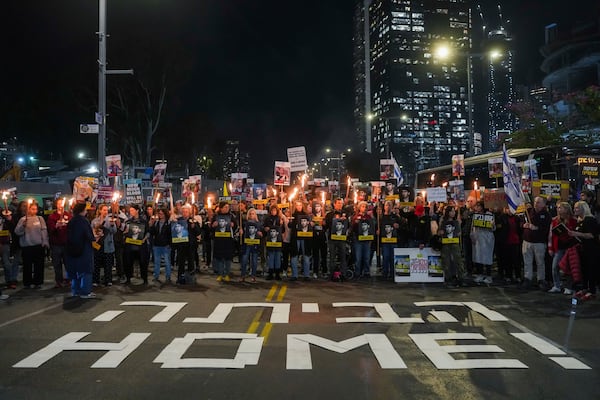 Demonstrators hold torches during a protest calling for the immediate release of the hostages held in the Gaza Strip by the Hamas militant group in Tel Aviv, Israel, on Monday, Jan. 13, 2025. (AP Photo/Ohad Zwigenberg)