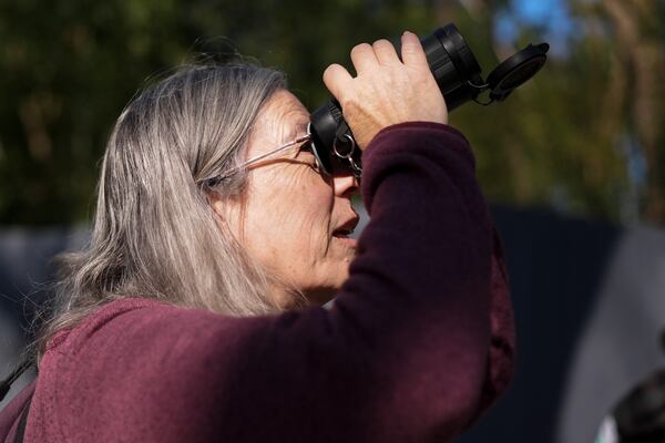 Diana Marbury-Sharp uses binoculars to watch sandhill cranes at the Wheeler National Wildlife Refuge, Monday, Jan. 13, 2025, in Decatur, Ala. (AP Photo/George Walker IV)