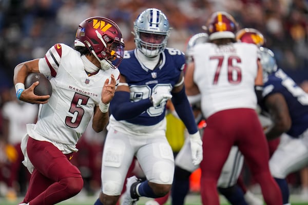 Washington Commanders quarterback Jayden Daniels (5) runs with the ball as Dallas Cowboys defensive end Chauncey Golston (99) chases him during the first half of an NFL football game, Sunday, Jan. 5, 2025, in Arlington, Texas. (AP Photo/Josh McSwain)