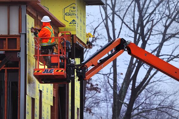 A construction worker is bundled up in winter clothes while installing weather sheathing on a building during a rain storm, Wednesday, Dec. 11, 2024, in Derry, N.H. (AP Photo/Charles Krupa)