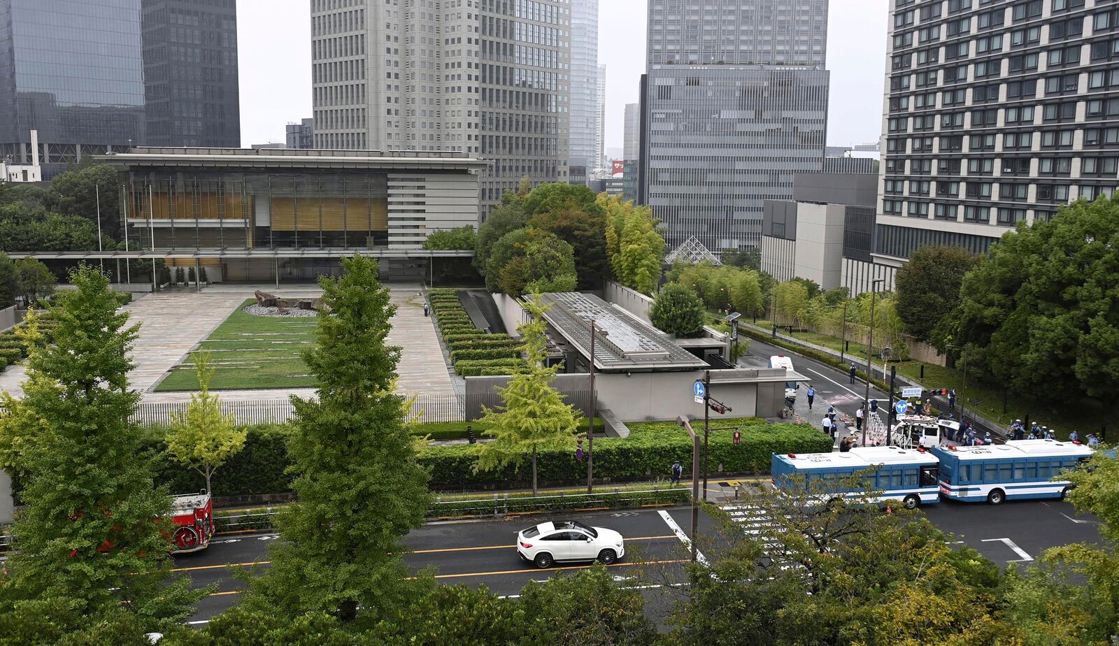 Officials work near a white vehicle, right above, which was stuck against a barricade near the prime minister's office in Tokyo Saturday, Oct. 19, 2024. (Kyodo News via AP)