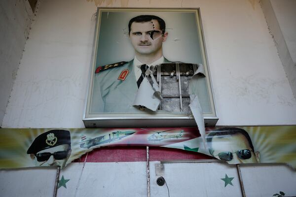 A torn posters shows the late Syrian President Hafez Assad and his son the ousted Syrian president Bashar Assad, that were set at the entrance of the notorious security detention centre called Palestine Branch, in Damascus, Syria, Saturday, Dec. 14, 2024. (AP Photo/Hussein Malla)