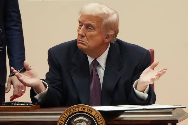 President Donald Trump gestures as he signs executive orders at an indoor Presidential Inauguration parade event in Washington, Monday, Jan. 20, 2025. (AP Photo/Matt Rourke)