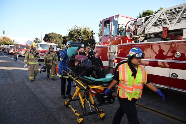 A woman is carried on a stretcher near the site of a plane crash, Thursday, Jan. 2, 2025, in Fullerton, Calif. (AP Photo/Kyusung Gong)