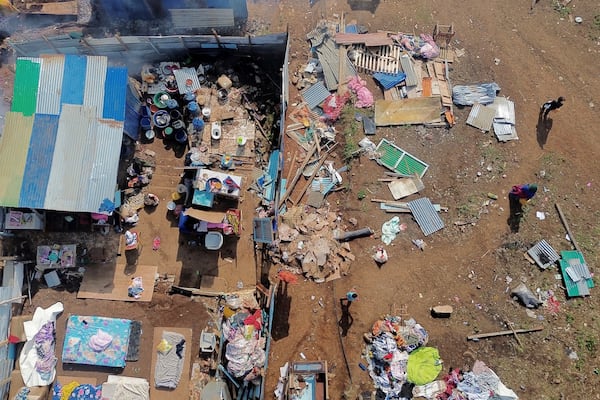 People walk by destroyed homes in the Barakani, Mayotte, informal settlement, Saturday, Dec. 21, 2024. (AP Photo/Adrienne Surprenant)