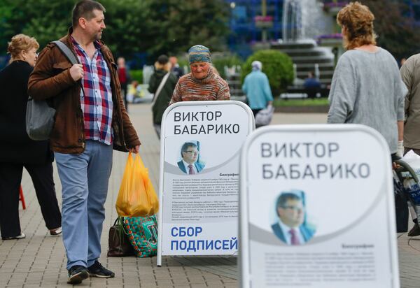 FILE - People walk past informational posters supporting Viktar Babaryka, who wanted to run in the upcoming presidential elections, in Minsk, Belarus, on June 14, 2020. (AP Photo/Sergei Grits, File)