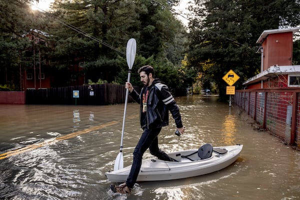 Tristan Millstone reacts as he steps in water after kayaking across a flooded section of Neely Road to buy groceries after a major storm in Guerneville, Calif., Saturday, Nov. 23, 2024. (Stephen Lam/San Francisco Chronicle via AP)