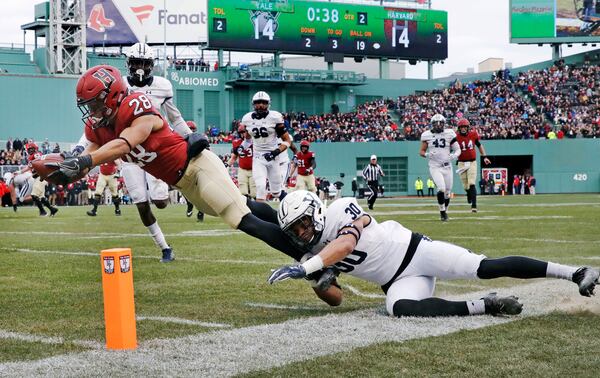 FILE - In this Nov. 17, 2018, file photo, Harvard wide receiver Henry Taylor (28) stretches for a touchdown against Yale linebacker Noah Pope (30) during the first half of an NCAA college football game at Fenway Park in Boston. (AP Photo/Charles Krupa, File)