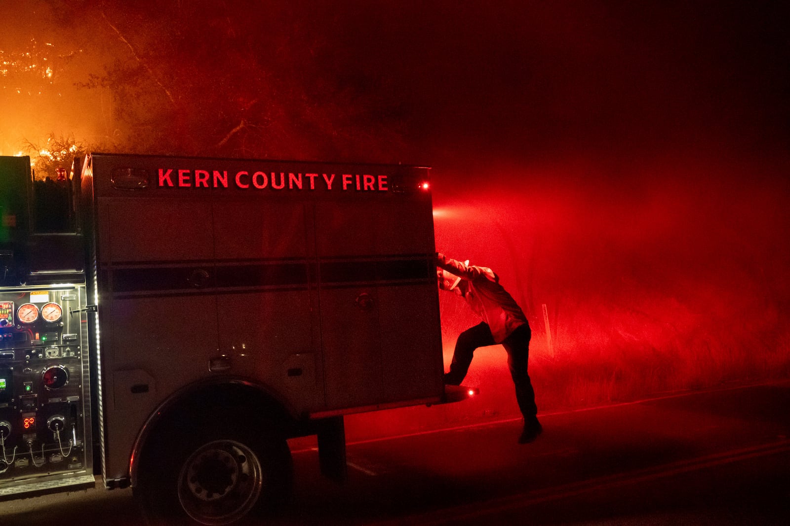 A firefighter climbs off an engine while battling the Mountain Fire on Wednesday, Nov. 6, 2024, in Santa Paula, Calif. (AP Photo/Noah Berger)