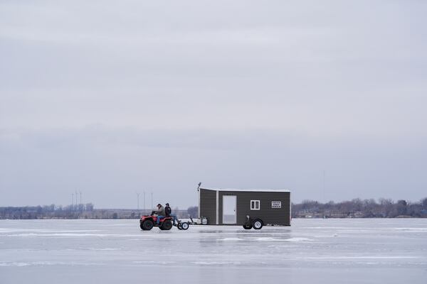 Long-time residents transport an ice fishing shed across the frozen Okabena Lake in Worthington, Minnesota, Saturday, Jan. 11, 2025. (AP Photo/Abbie Parr)