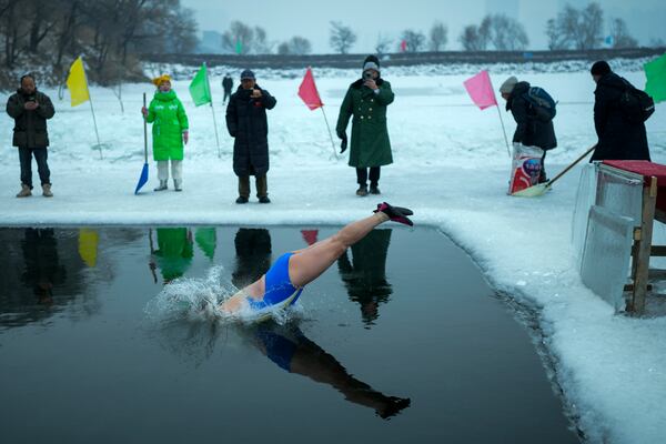 Residents watch a woman jump into a pool carved from ice on the frozen Songhua river in Harbin in northeastern China's Heilongjiang province, Tuesday, Jan. 7, 2025. (AP Photo/Andy Wong)