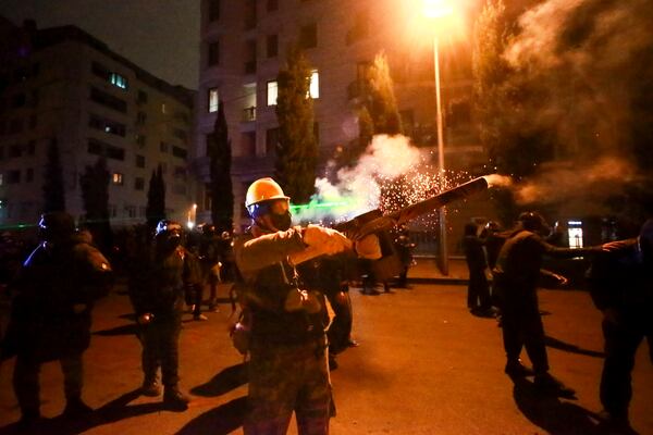 A demonstrator uses a firecrackers against police during a rally against the government's decision to suspend negotiations on joining the European Union for four years, outside the parliament in Tbilisi, Georgia, early Monday, Dec. 2, 2024. (AP Photo/Zurab Tsertsvadze)