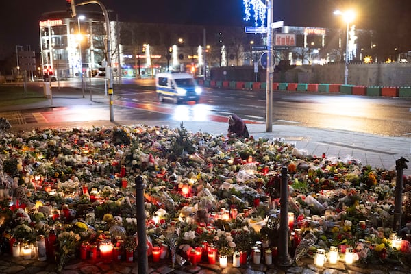 Candles, flowers and wreaths sit in front of the entrance to St. John's Church early Sunday, Dec. 22, 2024, in Magdeburg, Germany, after a car drove into a crowd at a Christmas market on Friday, Dec. 20. (Sebastian Kahnert/dpa via AP)