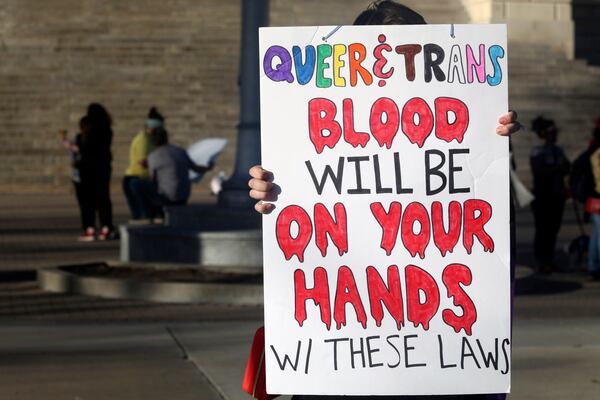 FILE - A protester outside the Kansas Statehouse holds a sign after a rally for transgender rights on the Transgender Day of Visibility, March 31, 2023, in Topeka, Kan. Kansas will no longer change transgender people's birth certificates to reflect their gender identities, the state health department said Friday, Sept. 15, 2023, citing a new law that prevents the state from legally recognizing those identities. (AP Photo/John Hanna, File)