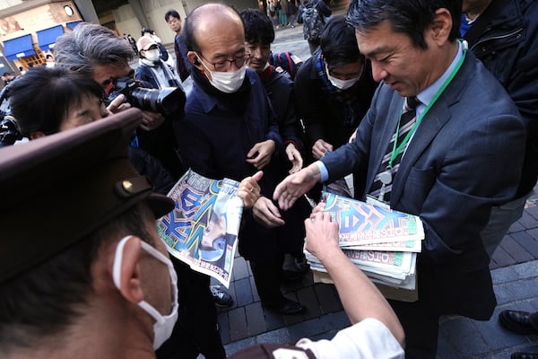 A staff member distributes an extra edition of the Sports Hochi newspaper reporting that Los Angeles Dodgers' Shohei Ohtani won his third Most Valuable Player award, Friday, Nov. 22, 2024, in Tokyo. (AP Photo/Eugene Hoshiko)