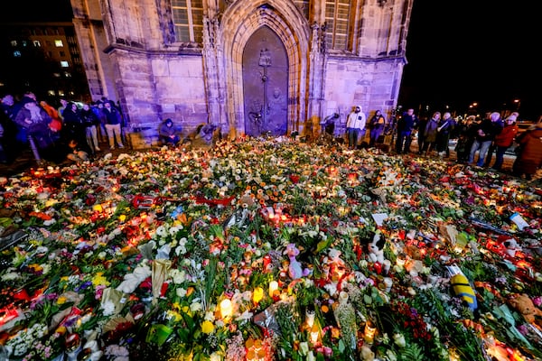 People have laid flowers and candles in front of the Johannis church close to the Christmas market, where a car drove into a crowd on Friday evening, in Magdeburg, Germany, Saturday, Dec. 21, 2024. (AP Photo/Michael Probst)