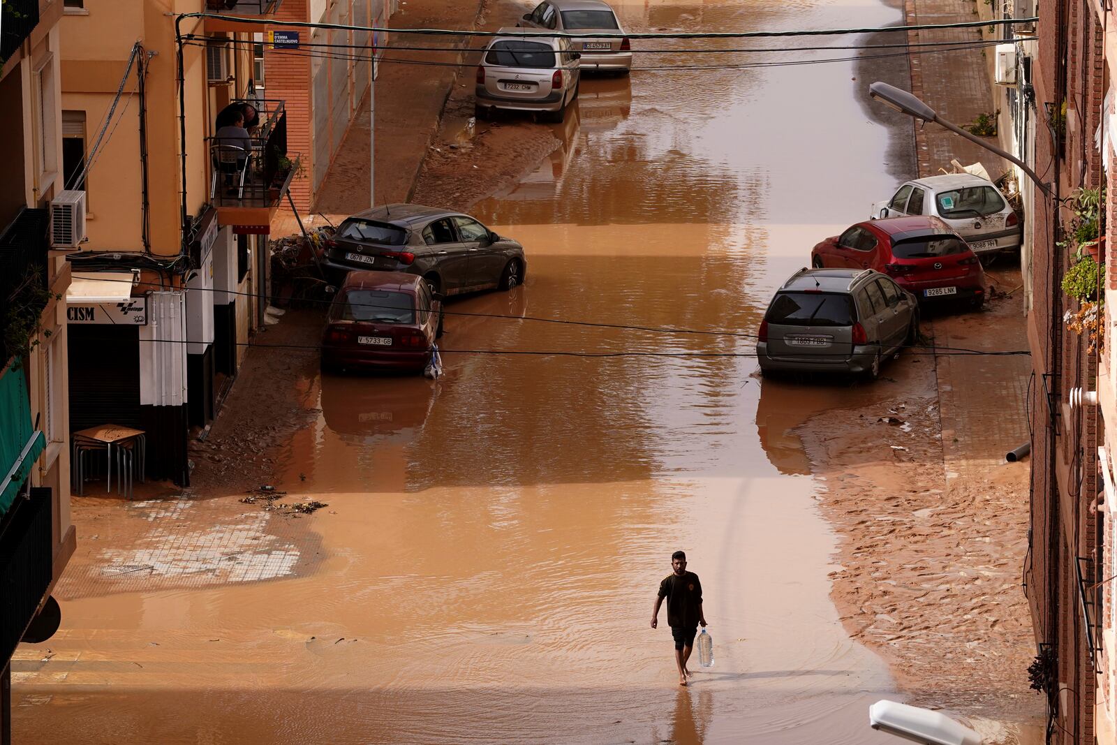 A man carrying water walks through flooded streets in Valencia, Spain, Wednesday, Oct. 30, 2024. (AP Photo/Alberto Saiz)