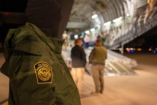 This photo provided by the U.S. Dept. of Defense, A U.S. Customs and Border Protection agent watches as undocumented immigrants are loaded onto a C-17 Globemaster III at Tucson International Airport in Tucson, Ariz., Thursday, Jan. 23, 2025. (Senior Airman Devlin Bishop/Dept. of Defense via AP)