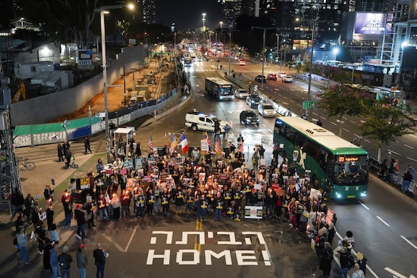 Demonstrators hold torches during a protest calling for the immediate release of the hostages held in the Gaza Strip by the Hamas militant group in Tel Aviv, Israel, on Monday, Jan. 13, 2025. (AP Photo/Ohad Zwigenberg)