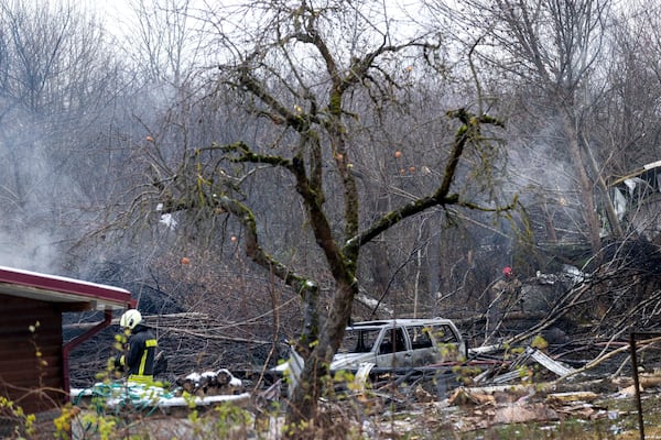 Lithuanian Emergency Ministry employees work near the place where a DHL cargo plane crashed into a house near the Lithuanian capital Vilnius, Lithuania, Monday, Nov. 25, 2024. (AP Photo/Mindaugas Kulbis)