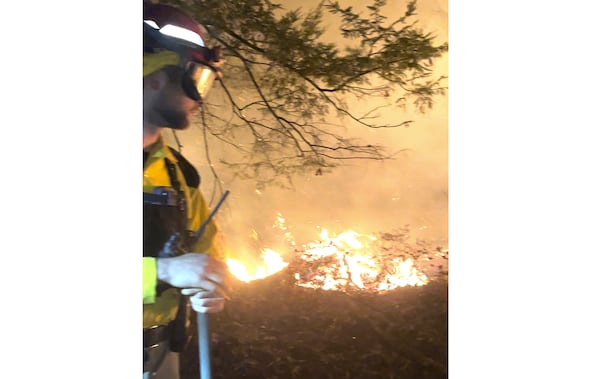 This image taken from video shows shows flames burning as a forest ranger works at the Jennings Creek wildfire, in Warwick, N.Y., Saturday, Nov. 16, 2024. (New York State Department of Environmental Conservation via AP)