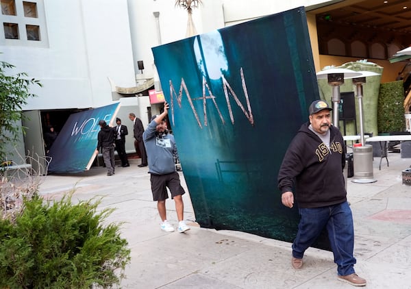 Crew members carry out signs for the new film "Wolf Man" after the premiere was cancelled due to high winds in the area on Tuesday, Jan. 7, 2025, at the TCL Chinese Theatre in Los Angeles. (AP Photo/Chris Pizzello)